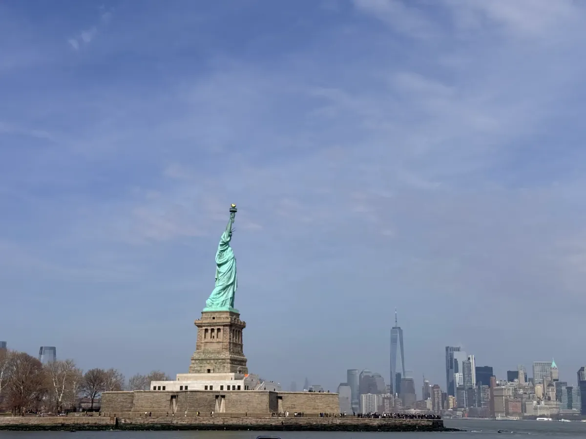 Iconic view of the Statue of Liberty with the New York City skyline in the background.