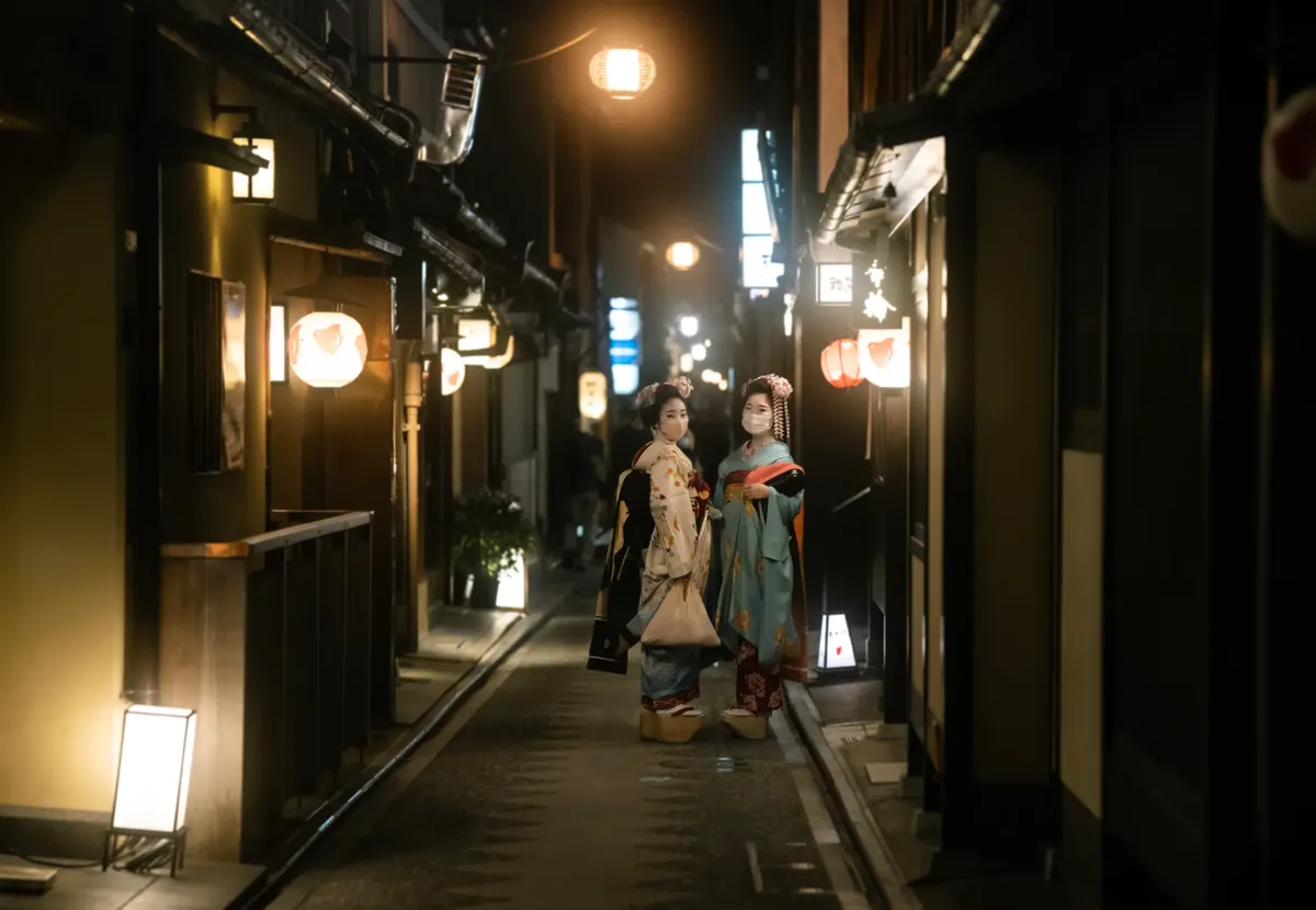 Two geishas stroll through Kyoto's atmospheric streets in traditional attire, capturing the essence of Japanese culture.